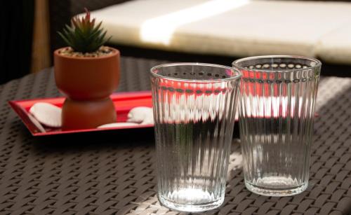 卡塔尼亚Mirage Mer B&B的两只清澈的玻璃杯坐在桌子上,放着盆子
