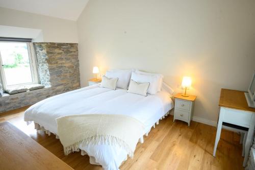 基拉尼Killarney Old School Road sleeps 6的一间卧室配有一张带两盏灯的大型白色床。