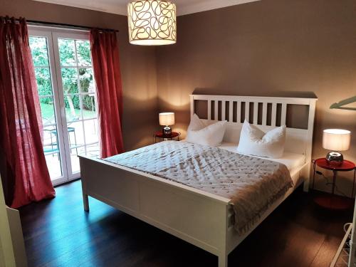 森夫滕贝格Seeliebe mit Sauna und nur 50 mtr. bis zum Strand的卧室配有一张带红色窗帘的大型白色床