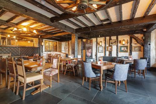 BolventorThe Jamaica Inn, Bodmin, Cornwall的餐厅设有木桌、椅子和天花板