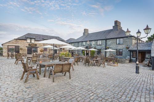 BolventorThe Jamaica Inn, Bodmin, Cornwall的一个带桌椅和遮阳伞的户外庭院。