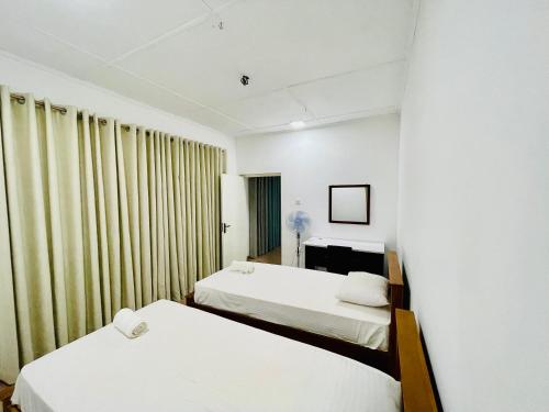 努格古达The Colombo Home的配有白色墙壁和窗帘的客房内的两张床