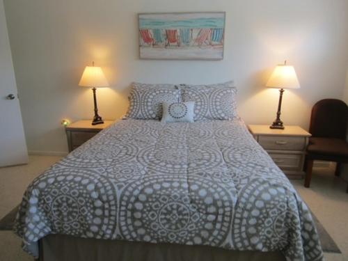 霍姆斯海滩Steps from the Gulf of Mexico的一间卧室配有一张带两盏灯和两张桌子的床。