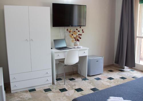 卡塔尼亚Mirage Place B&B的一间卧室配有一张带笔记本电脑的桌子和一台电视机。
