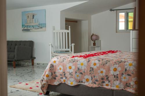 Cidade VelhaCidade Paradise Guesthouse的一间卧室配有一张带毯子和椅子的床