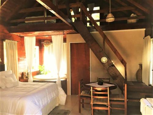 兰舒凯马杜Cabana dos Sonhos na Serra SC的一间卧室配有一张床、一张桌子和一个楼梯