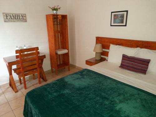ApanecaHostal Puertas De Apaneca的一间卧室配有一张床、一张桌子和一把椅子