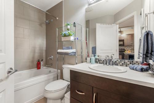 卡尔加里City Centre Retreat - 1BR Condo with Desk的浴室配有盥洗盆、卫生间和浴缸。