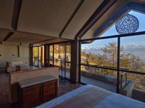 纳加阔特Kavya Resort & Spa的一间卧室设有床铺和大型玻璃窗