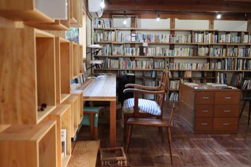南淡路市猫と図書館のある宿 草地家 Kusachike的图书馆配有书桌、椅子和书架