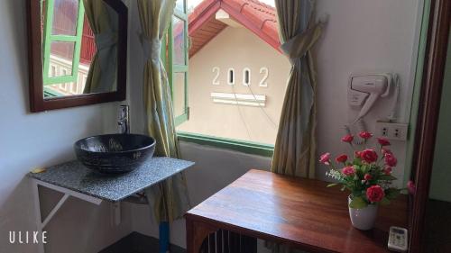 琅勃拉邦Villa Thavisouk Legend - Luang Prabang的浴室设有水槽,桌子上放着花瓶