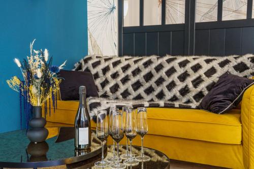 图尔Le Baleschoux - PrestiPlace Tours的黄色的沙发,配有带酒杯的桌子