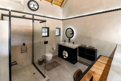 卡萨内Chobe River Lodge的一间带水槽、淋浴和时钟的浴室