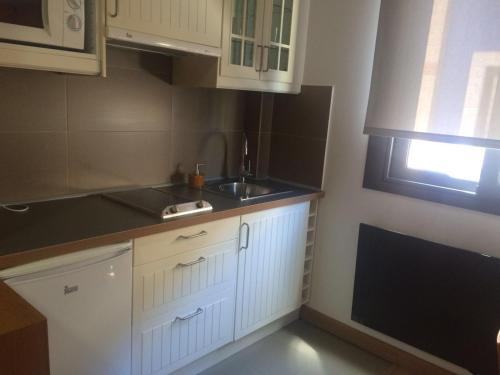 康达Alojamientos Maramar的厨房配有白色橱柜、水槽和窗户。