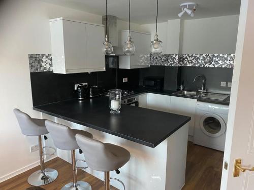 格拉斯哥Perfectly situated luxury 2 bedroom apartment的厨房配有黑色柜台和2个吧台凳
