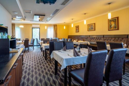 希克洛什Hotel Castello & Thermal Spa Siklós的一间在房间内配有桌椅的餐厅