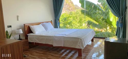 峰牙Phong Nha Moonlight Villas的一间卧室设有一张床和一个大窗户