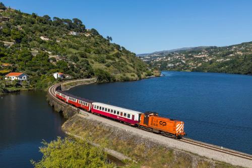 卡尔达斯德阿雷戈斯Chalé Caldas de Aregos的一条橙色和白色的火车在湖边