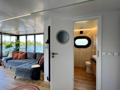 芬克芬NEW - Little Asia - Stunning Boathouse on al lake Near Amsterdam的客厅设有蓝色的沙发和窗户。