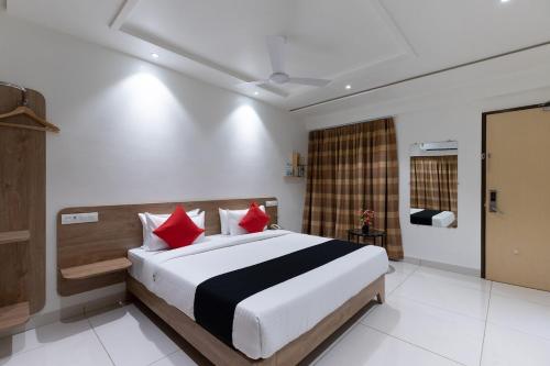 贾姆讷格尔Sapphero Akshar Inn- Jamnagar的一间卧室配有一张带红色枕头的大床