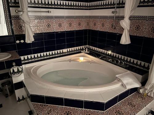 伊斯费古耶拉尔海滩恩卡特德尔里约庄园公寓的浴室设有浴缸,铺有黑色和白色瓷砖。