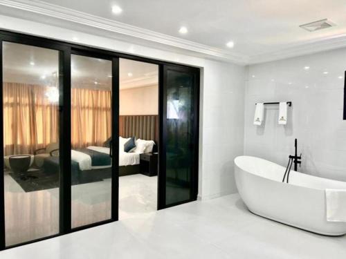 ElwaLifestyle Luxury Hotel and Residence的带浴缸的白色浴室和卧室
