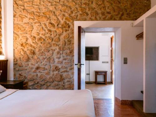 伊维萨镇Can Pep Luis Can Pep Mortera is located in the beautiful countryside near to Playa den Bossa的一间卧室设有一张床和石墙