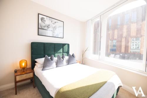 利兹Velvet Apartments - 56 Vicar Lane的一间卧室配有一张带绿色床头板的床和窗户