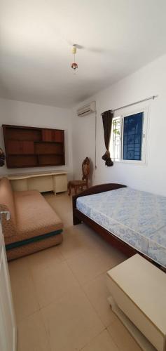 苏塞Chouette villa au bord de la plage hergla的一间卧室配有一张床、一张沙发和一个窗口