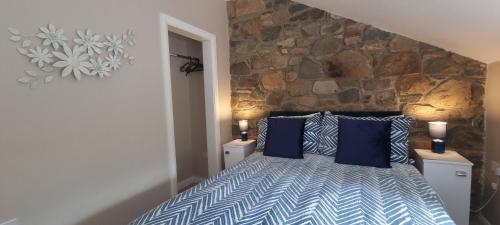 BallynahinchFrontview Cottage - Sleeps 6的一间卧室配有一张带蓝色枕头的床和石墙