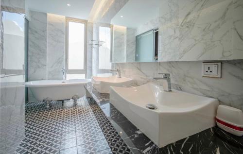土龙木市Feliz Hotel Binh Duong的白色的浴室设有两个水槽、一个浴缸和一个浴缸。