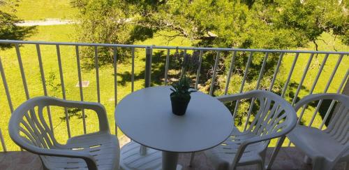 格雷乌莱班Studio lou paradou residence le provence的阳台上的白色桌椅和盆栽植物