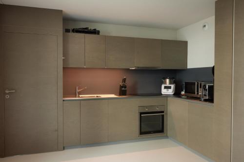 尼翁NYON - Appartement meublé tout confort的厨房配有棕色橱柜和水槽