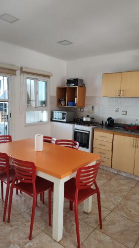 伊瓜苏港Casa con Garage Puerto Iguazú, zona residencial的厨房配有木桌和红色椅子