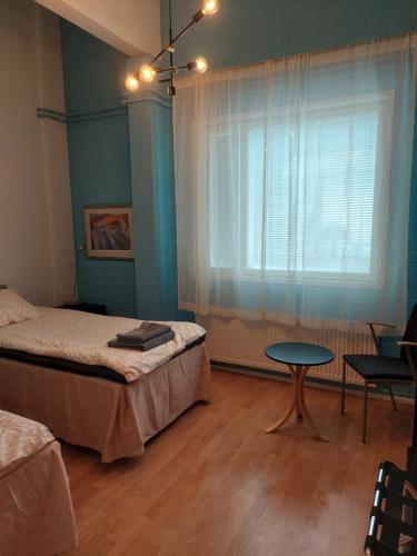 JoutsaKahvila ja Majoitus Tmi Tiina Soilu的一间卧室配有一张床、一张桌子和一个窗户。