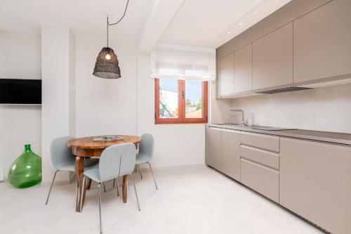 罗维尼Contrada del Nonno Apartments (city center - private parking on-site)的白色的厨房配有木桌和椅子