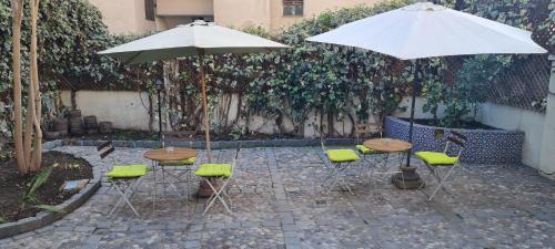 圣地亚哥Casa Ribera Hotel Providencia的庭院里配有两张桌子和椅子以及遮阳伞