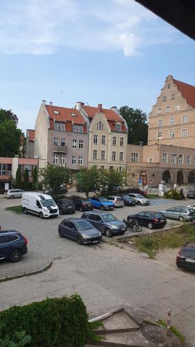 奥尔什丁Apartament Olsztyn Centrum的停车场,停车场的汽车停在大楼前