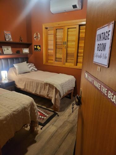 卡曼杜卡亚Chalé Colorado Vibe的一间设有两张床的房间,门上有一个标志