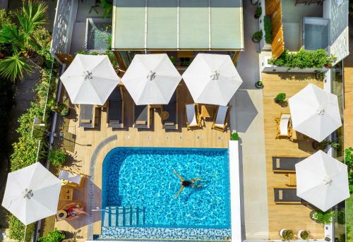 罗希姆诺Calla Luxury Seafront Suites的享有带白色遮阳伞的游泳池的顶部景致