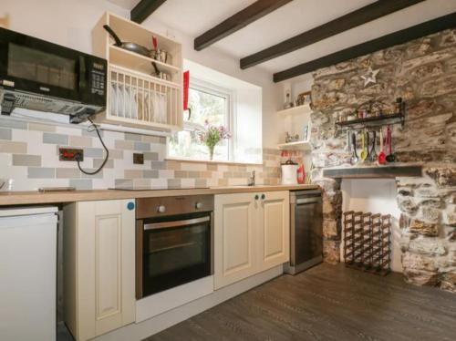 Saint BlazeyMiddleway Cottage的厨房配有白色橱柜和石墙