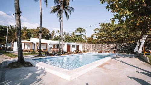 拉利伯塔德Coco Surf Tropical Village的一座棕榈树游泳池和一座房子