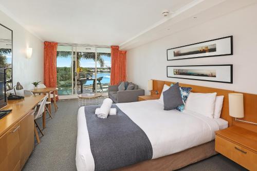 卡伦德拉Pelican Waters Golf Resort的一间带一张床和一张书桌的卧室和一间厨房