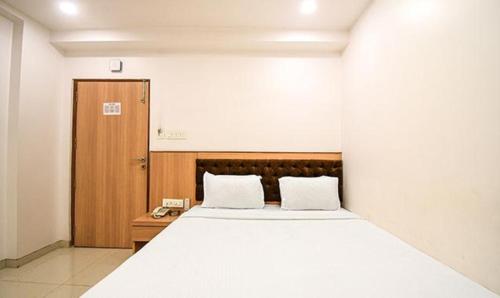 加尔各答FabHotel Stay Inn International的卧室配有一张白色大床和木门