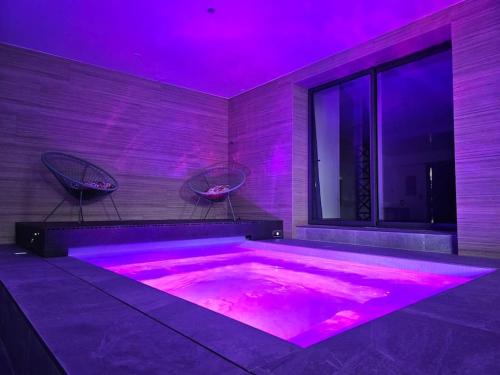 Villa & Spa Luxuria的紫色照明的客房内的热水浴池