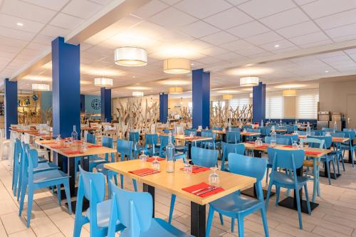 波尔尼谢Azureva Pornichet Baie de La Baule的一间配备有桌子和蓝色椅子的用餐室