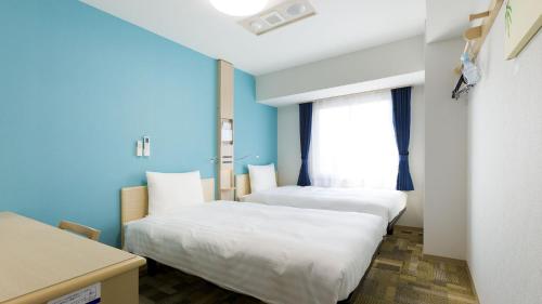 府中市Toyoko Inn Tokyo Keio-sen Higashi-fuchu-eki Kita-guchi的配有两张床铺的蓝色墙壁和窗户