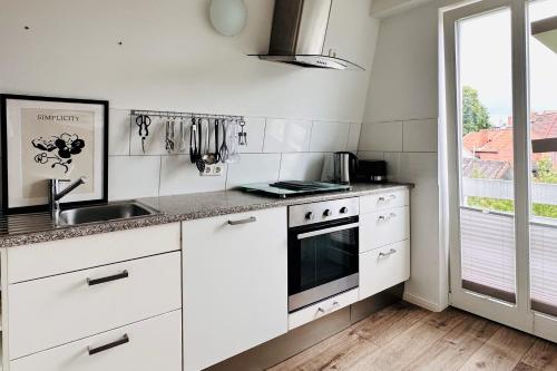 施塔德Der Stader Hafenblick的厨房配有白色橱柜、水槽和窗户。
