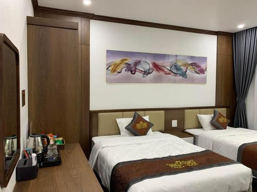 下龙湾Anika Hotel的酒店客房设有两张床,墙上挂有绘画作品