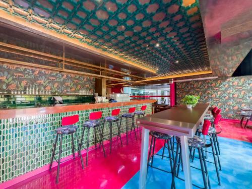 曼谷Ramada by Wyndham Bangkok Ten Ekamai Residences的一间酒吧,餐厅里摆放着红色的椅子和桌子
